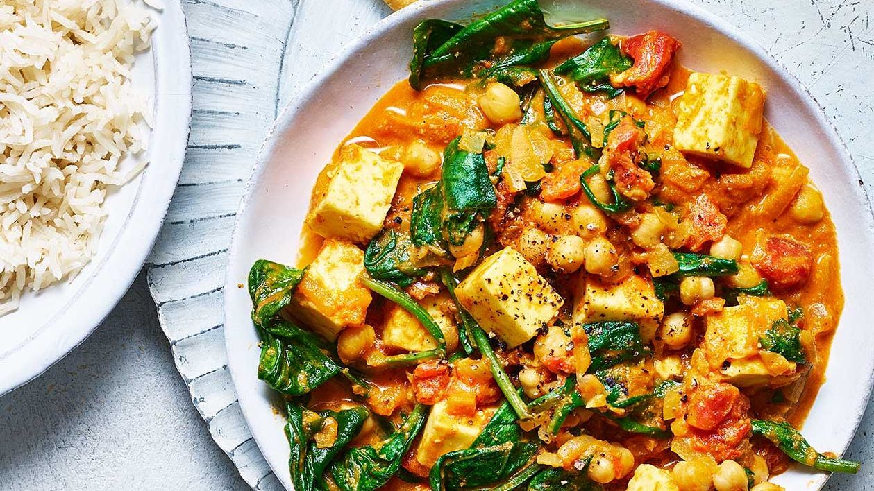 Karma bowl ingredients with paneer, chickpeas, and greens in a rich curry