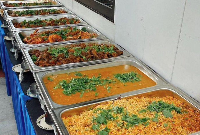 A full Indian buffet spread with rice, curries, and grilled items laid out for service