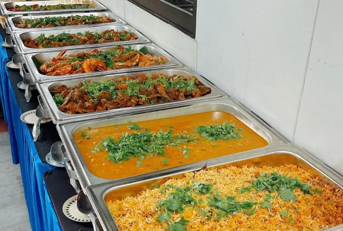 A full Indian buffet spread with rice, curries, and grilled items laid out for service