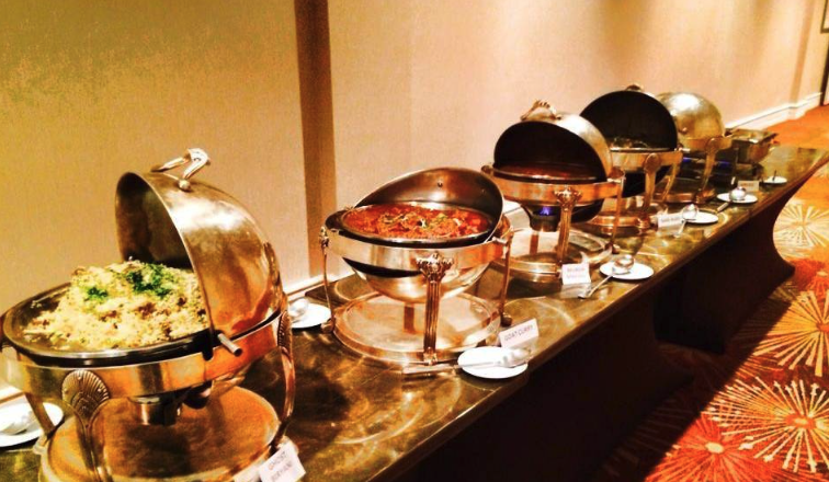 A long buffet line with gold chafers arranged for catered service