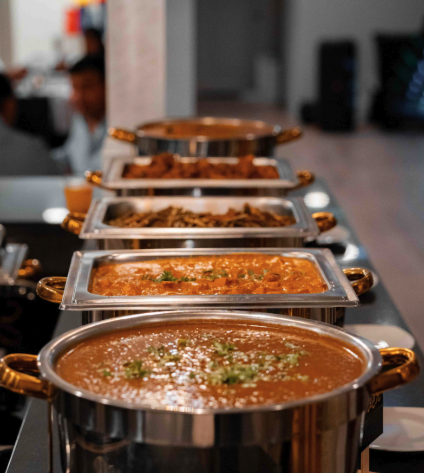 A vertical lineup of buffet warmers filled with curries and catering dishes