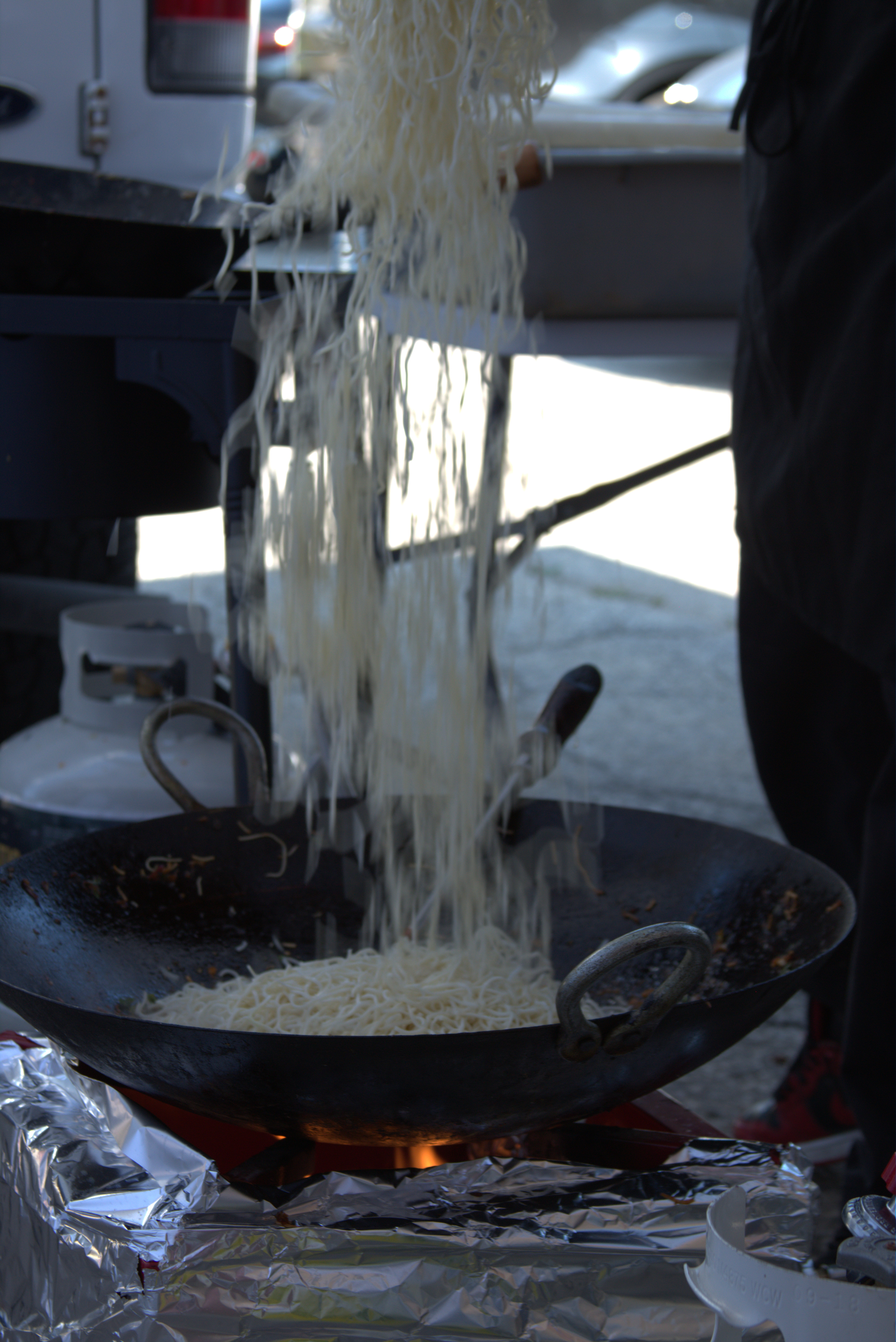 Noodles being finished in a wok over flame at a live event station
