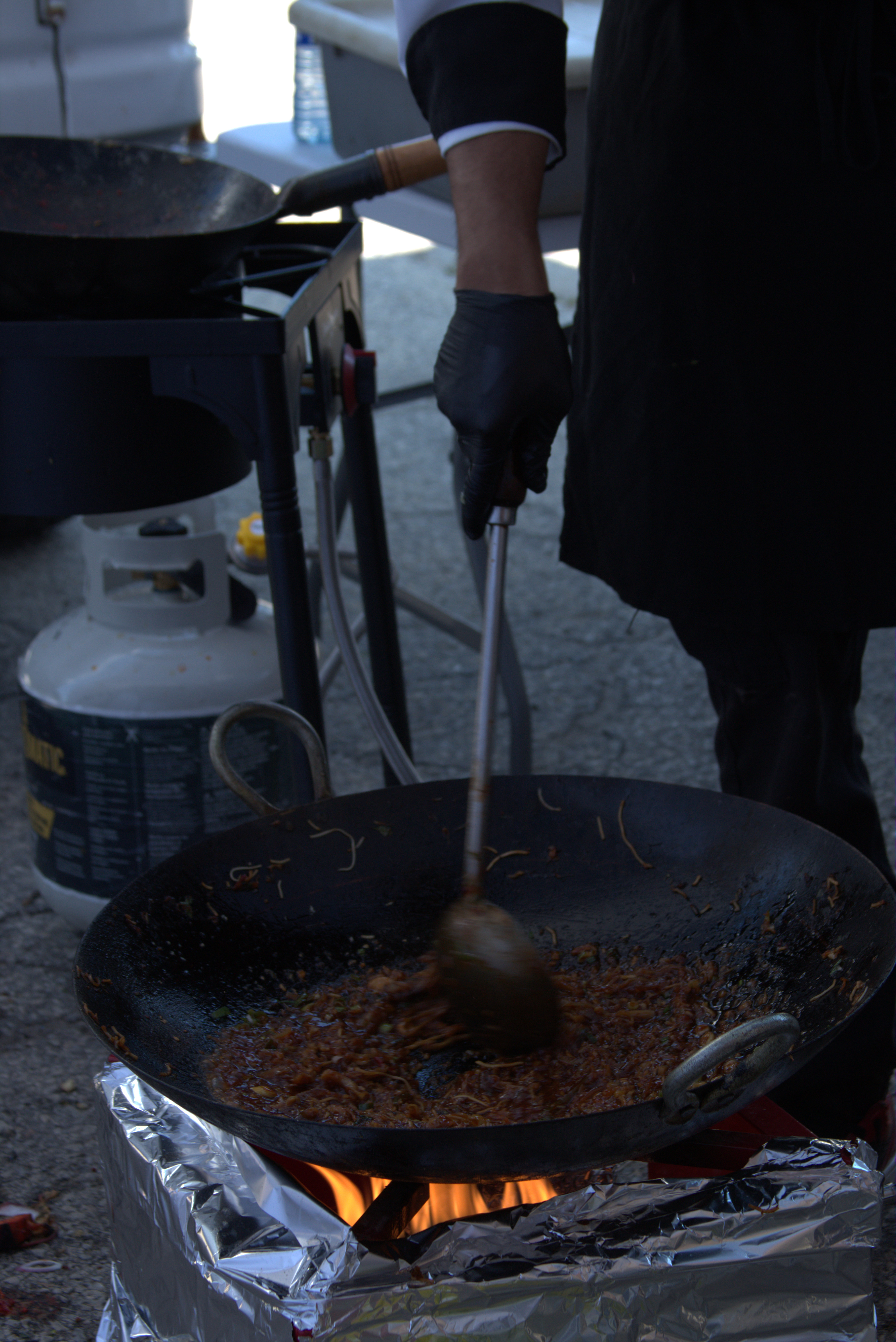 Sauce being worked in a hot pan at an outdoor live catering station