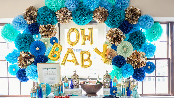 A baby shower dessert and drinks table set beneath a blue balloon backdrop