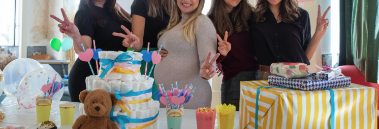 Guests posing beside a baby shower gift and dessert display