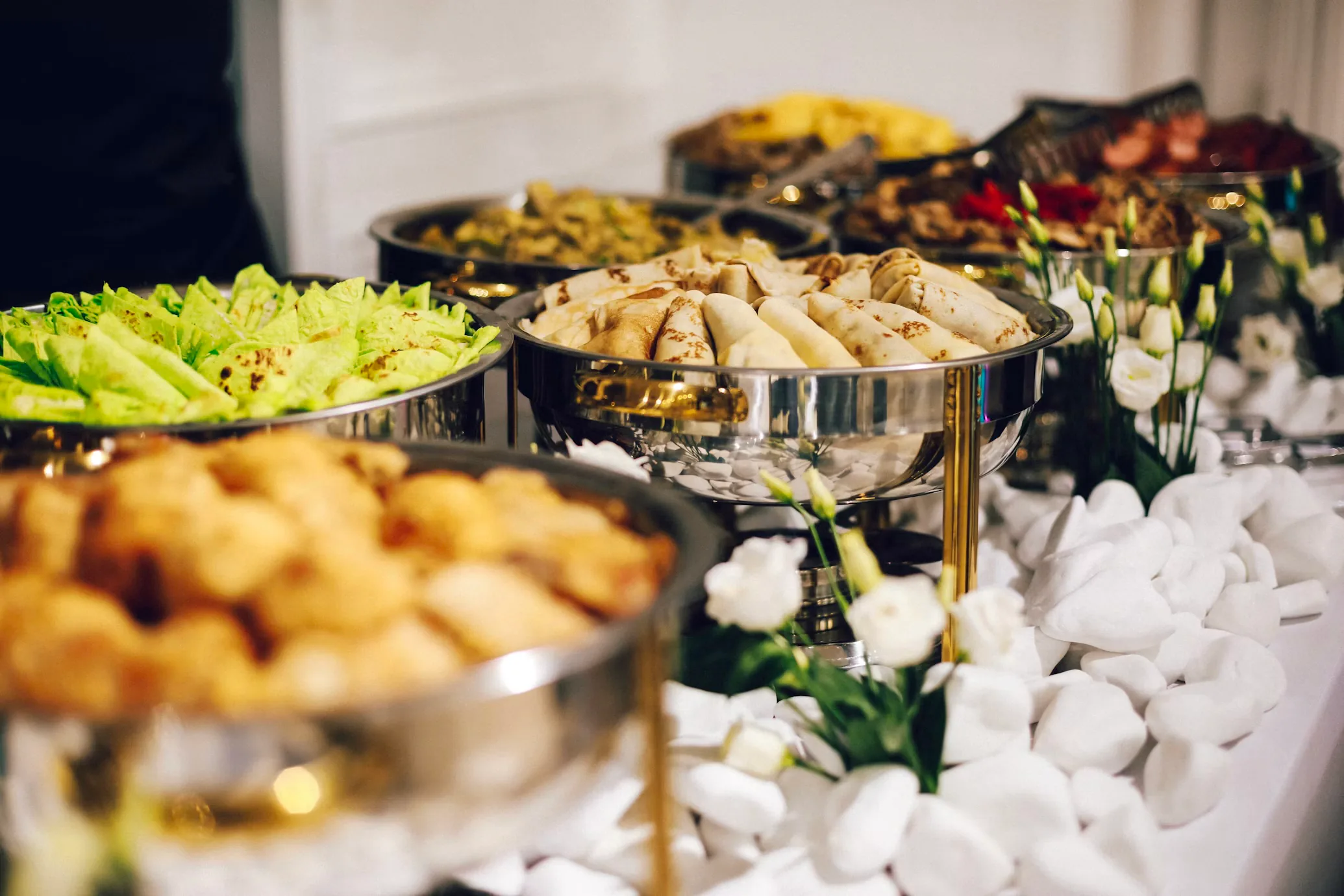A birthday-event buffet with folded flatbreads, hot trays, and floral decor arranged for a family celebration