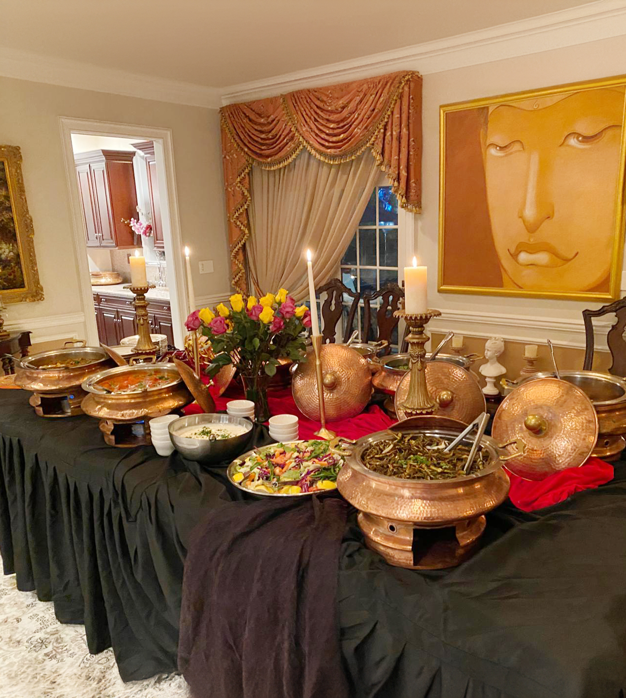 Copper chafers, curries, salad, and candlelit decor arranged across a buffet for an indoor birthday dinner