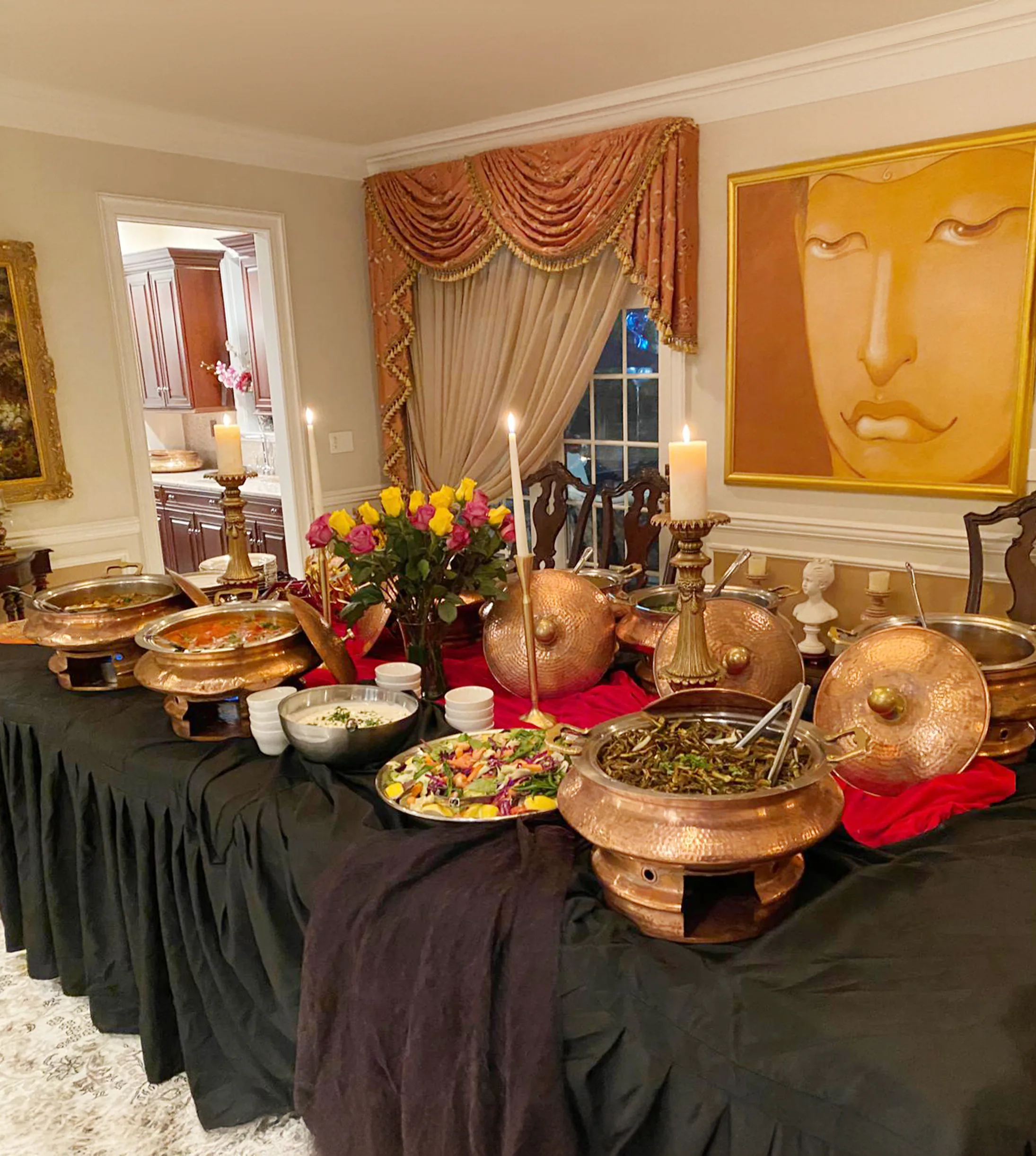 Copper chafers, curries, salad, and candlelit decor arranged across a buffet for an indoor birthday dinner