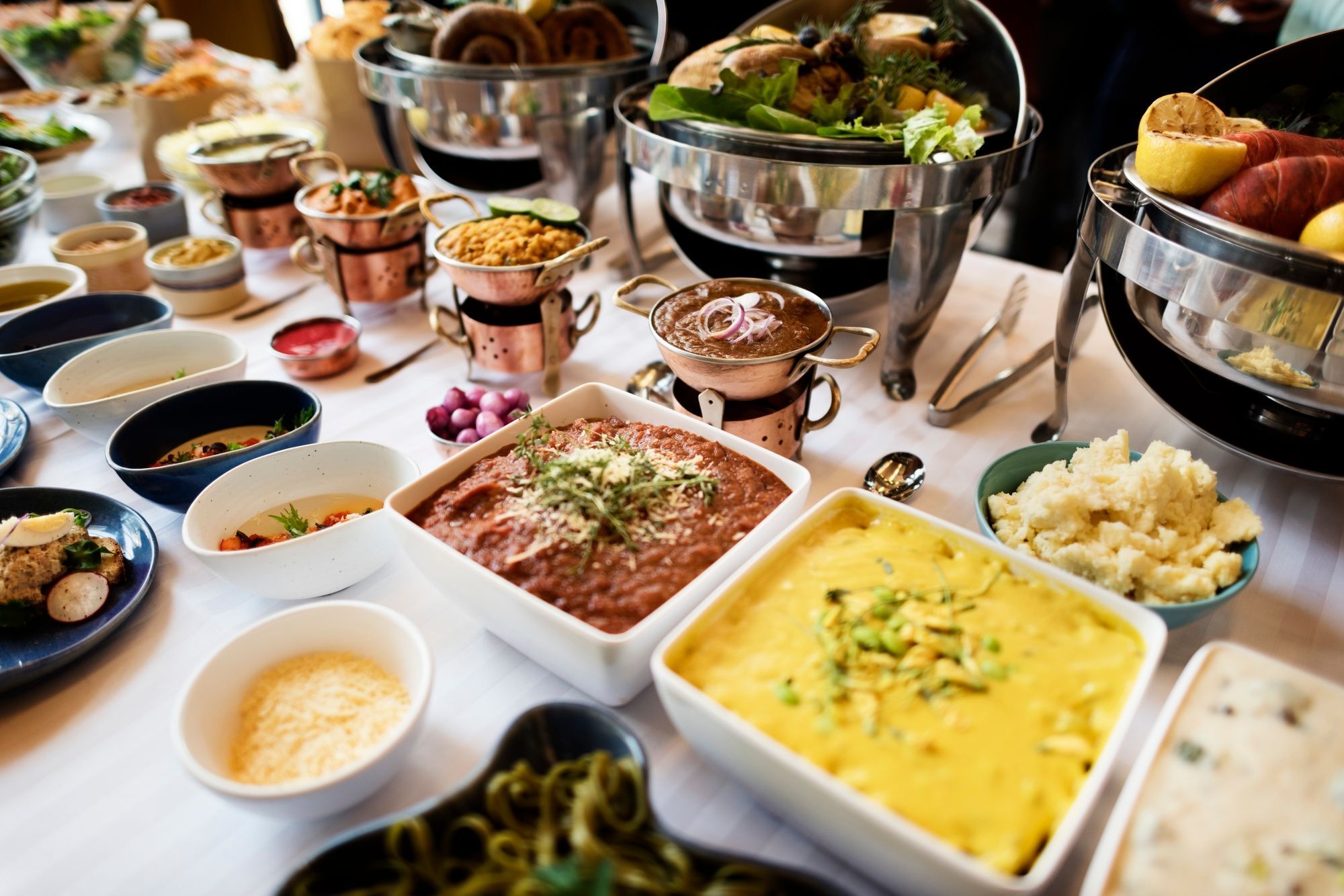 A birthday-party spread with plated bites, desserts, salads, and Indian dishes laid out across a long buffet table