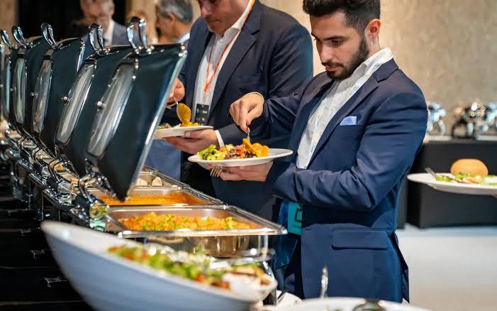 Corporate guests serving themselves from a polished chafer buffet line at an indoor business event