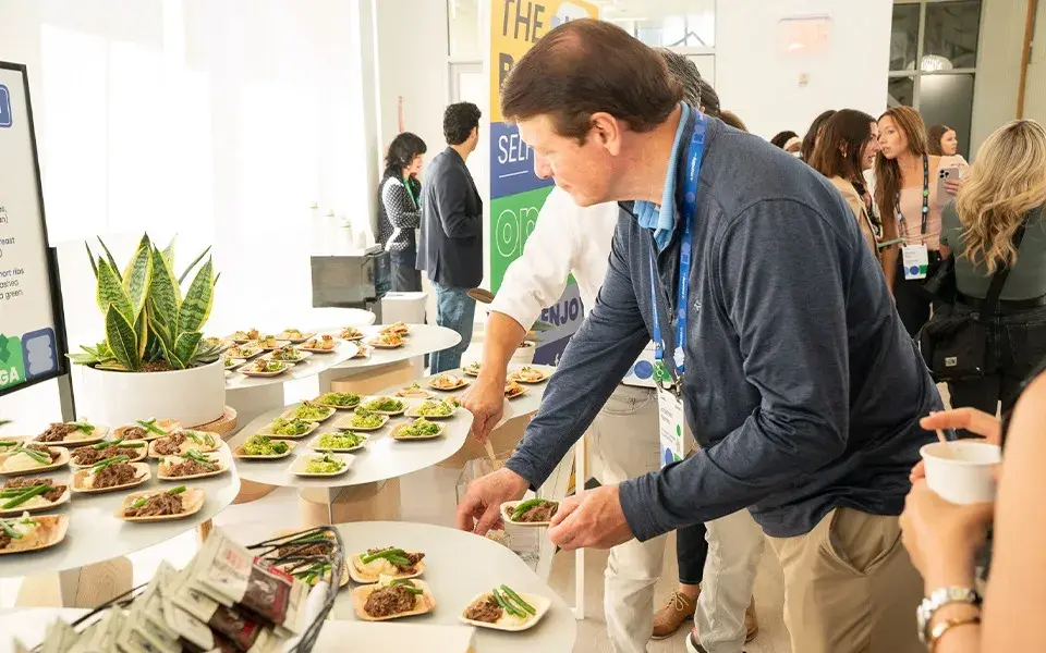 Attendees selecting plated tasting bites from a tiered catering display during a corporate event