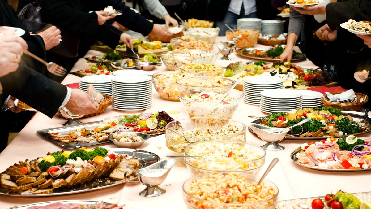 A memorial luncheon table with trays, salad, rolls, and place settings arranged for a considerate family gathering