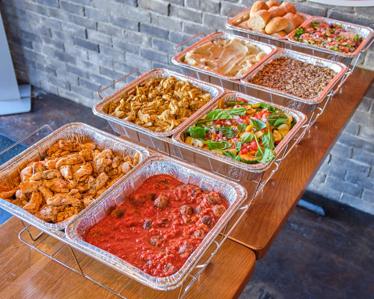 Graduation party buffet trays with hot entrees, salad, and rolls arranged on risers for service