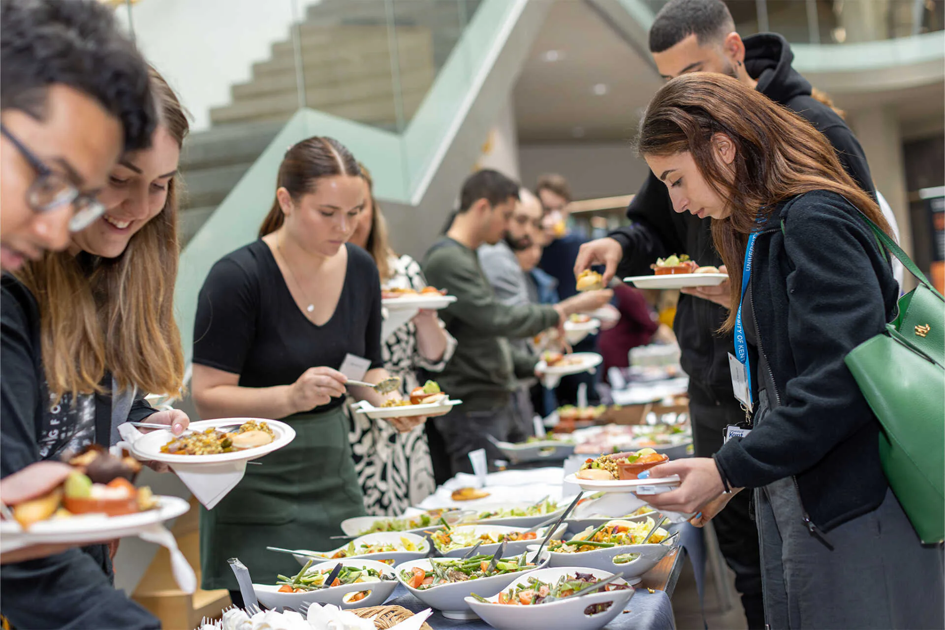 Students moving through a buffet line with plated salads and lunch items inside a bright campus atrium