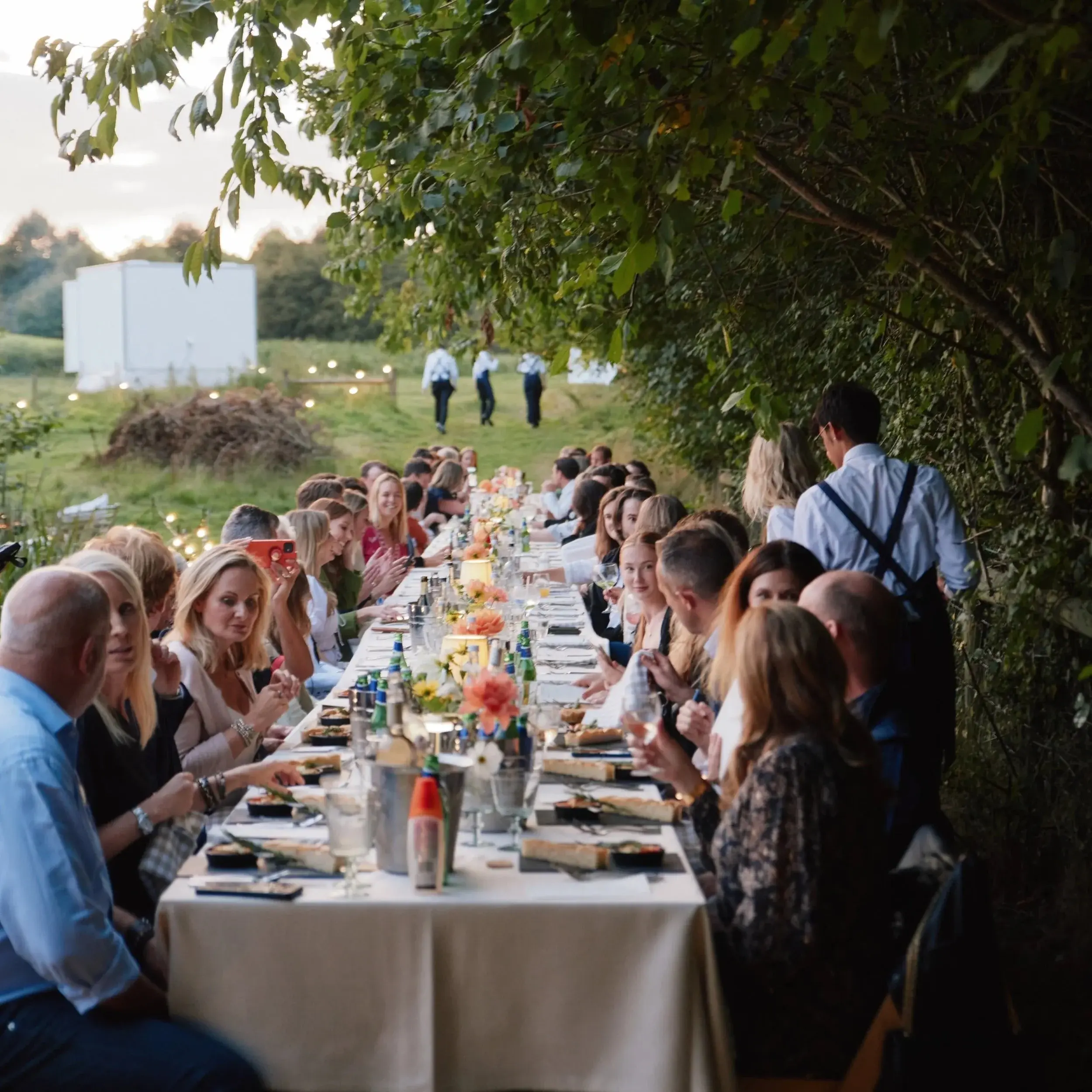 Guests gathering around a buffet and small plates spread inside a lively private-event tent
